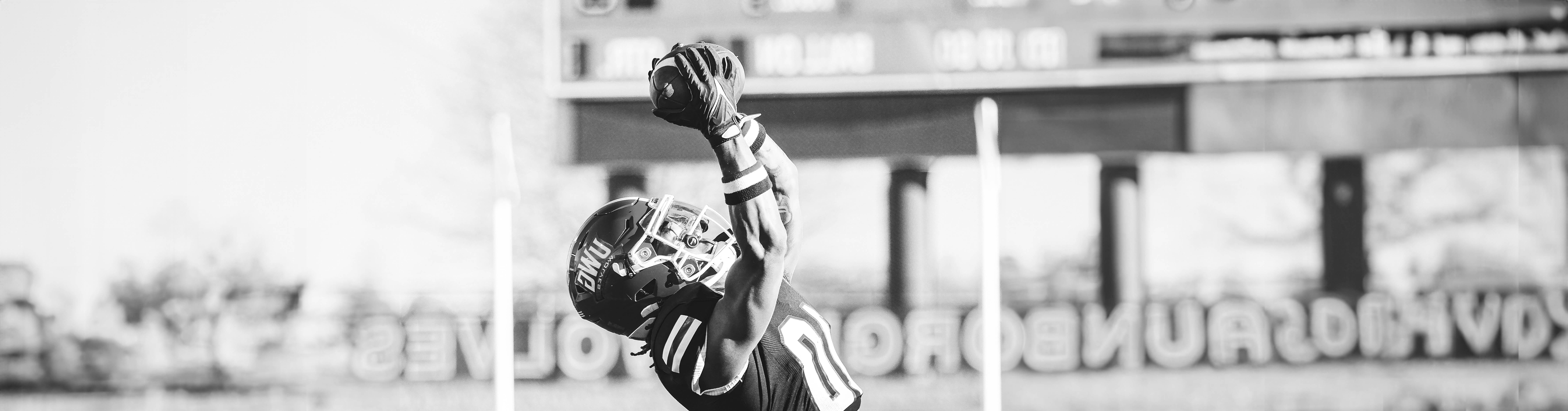 博彩平台推荐 Football Player jumping into the air to catch the football.